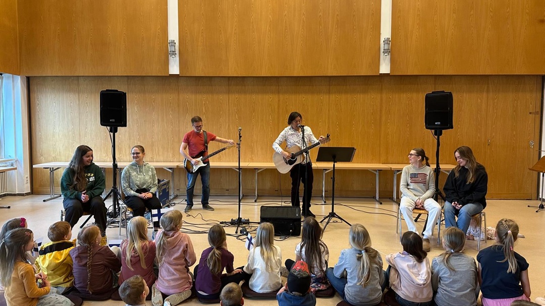 Lastenmusiikkia soittava bändi, jota seuraa lukuisa joukko lapsia.