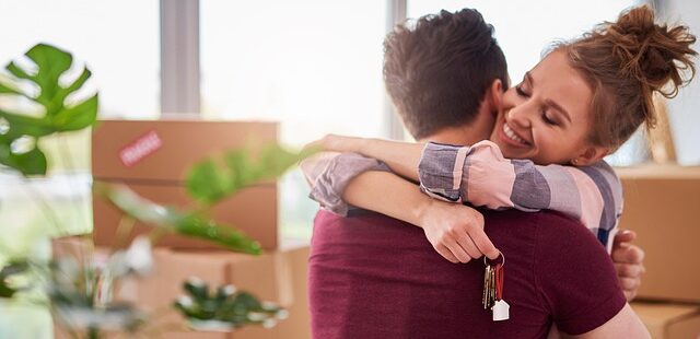 Pariskunta halaa toisiaan muuttolaatikoiden keskellä