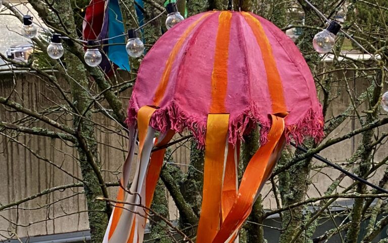 Käsintehty lyhty ja lamppuja puussa, jossa ei ole lehtiä.