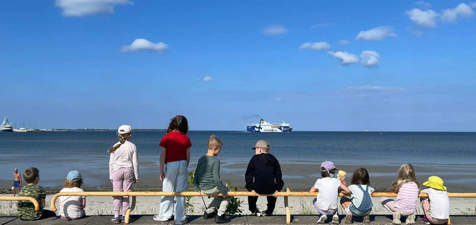 Tallinnan suomalaisen koulun oppilaita oppitunnilla ulkona meren äärellä. Taustalla Eckerölinen laiva tulossa satamaan.